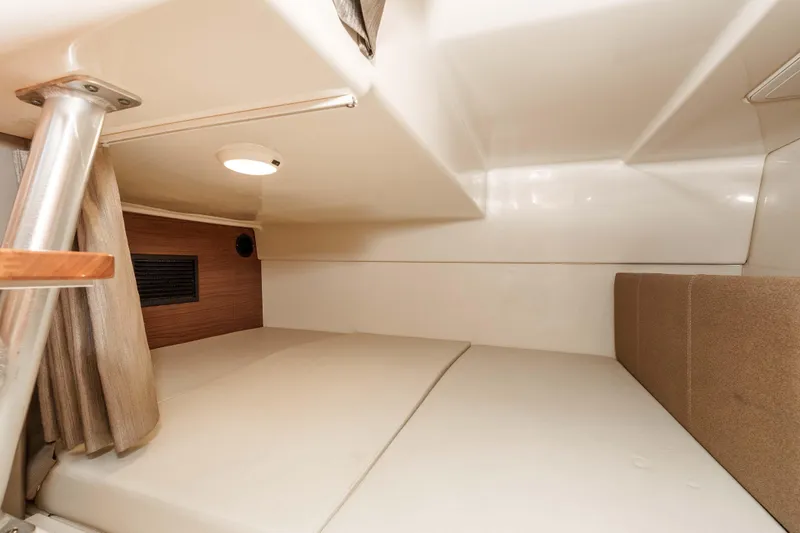 A Day In The Life Yacht Photos Pics 2021 Boston Whaler 325 Conquest cabin interior with cushioned sleeping area and wooden accents.