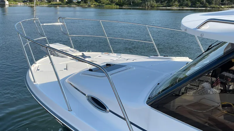  Yacht Photos Pics 2022 Cutwater C-32 Sedan boat on calm water, showcasing sleek design and railing.