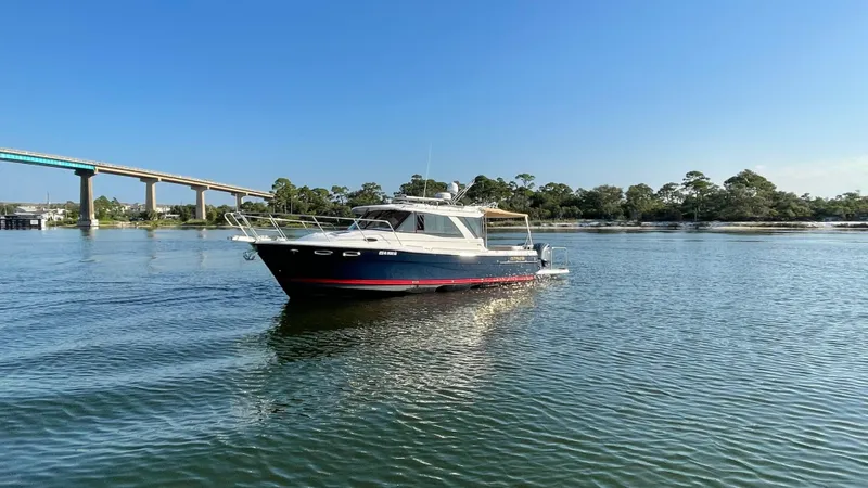  Yacht Photos Pics 2022 Cutwater C-32 Sedan boat on calm water with bridge and trees in background.