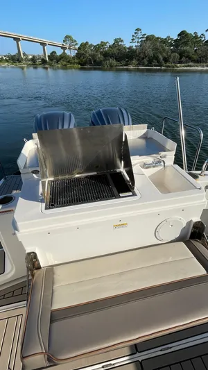  Yacht Photos Pics 2022 Cutwater C-32 Sedan boat with outdoor grill and seating, docked by a scenic river.