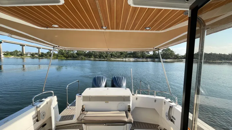  Yacht Photos Pics 2022 Cutwater C-32 Sedan boat with canopy, overlooking serene water and distant bridge.
