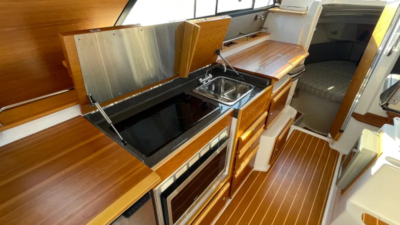  Yacht Photos Pics 2022 Cutwater C-32 Sedan interior with modern kitchen, wood finish, and cozy sleeping area.