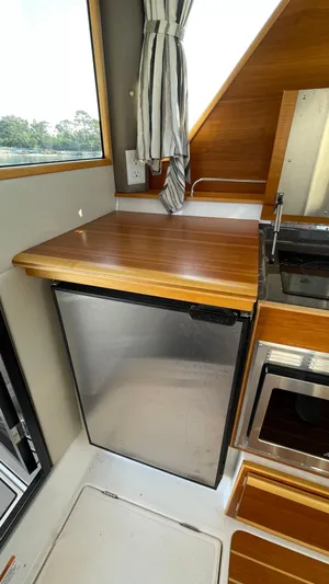  Yacht Photos Pics 2022 Cutwater C-32 Sedan kitchen with wood countertop, stainless steel fridge, and microwave.
