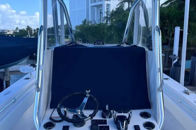  Yacht Photos Pics 2024 Contender 30 Tournament boat console with steering wheel and controls, docked near palm trees.