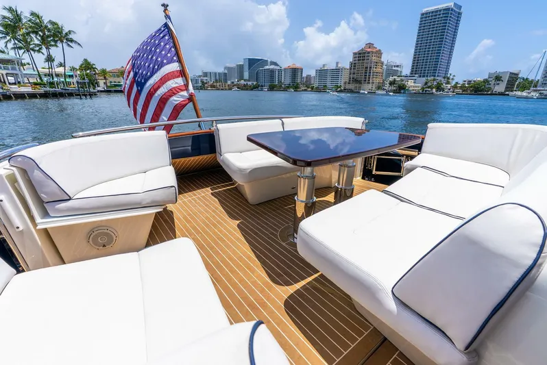 Shaken Not Stirred Yacht Photos Pics 2019 Zeelander Z55 yacht deck with seating, table, and American flag, overlooking waterfront cityscape.
