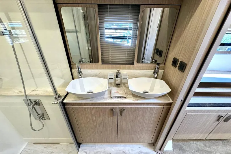  Yacht Photos Pics Modern bathroom with dual sinks, mirrors, and wooden cabinetry in a 2026 Prestige F4.9 model.