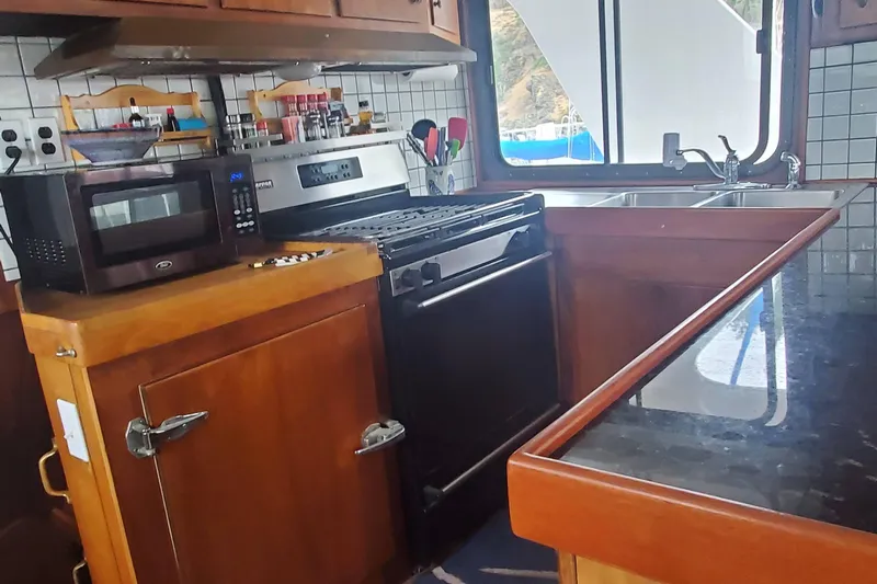 Regal Countess Yacht Photos Pics 1965 Tacoma Boat Works Bill Garden Motor Yacht kitchen with stove, microwave, and wooden cabinetry.