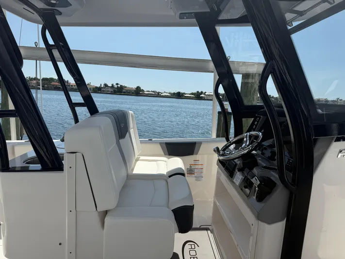 272-203 Brokerage Sebastian Yacht Photos Pics 2023 Robalo R272 Center Console boat interior with white seating and steering wheel, overlooking water.