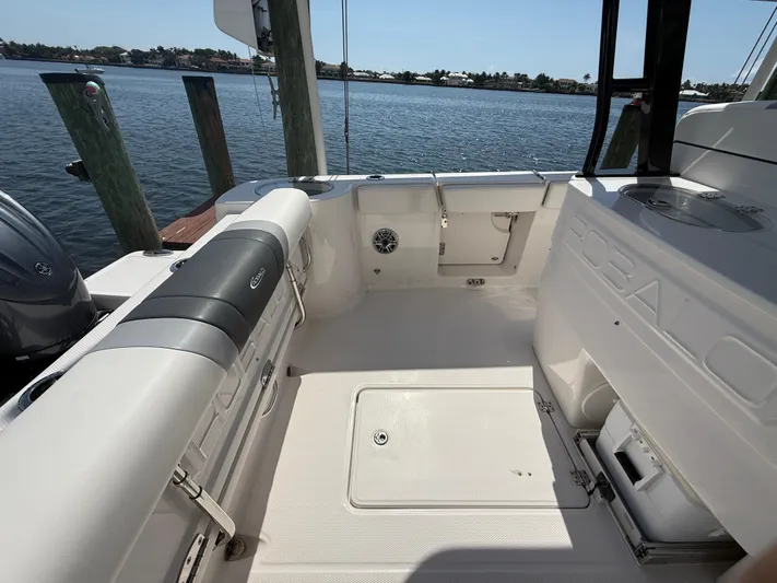 272-203 Brokerage Sebastian Yacht Photos Pics 2023 Robalo R272 Center Console boat interior with seating and storage, docked by the water.