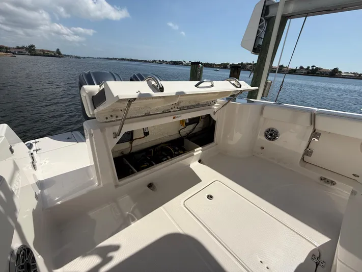 272-203 Brokerage Sebastian Yacht Photos Pics 2023 Robalo R272 Center Console boat with open storage compartment, docked by a scenic waterfront.