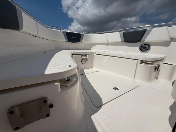 272-203 Brokerage Sebastian Yacht Photos Pics 2023 Robalo R272 Center Console boat interior with seating and storage under cloudy sky.
