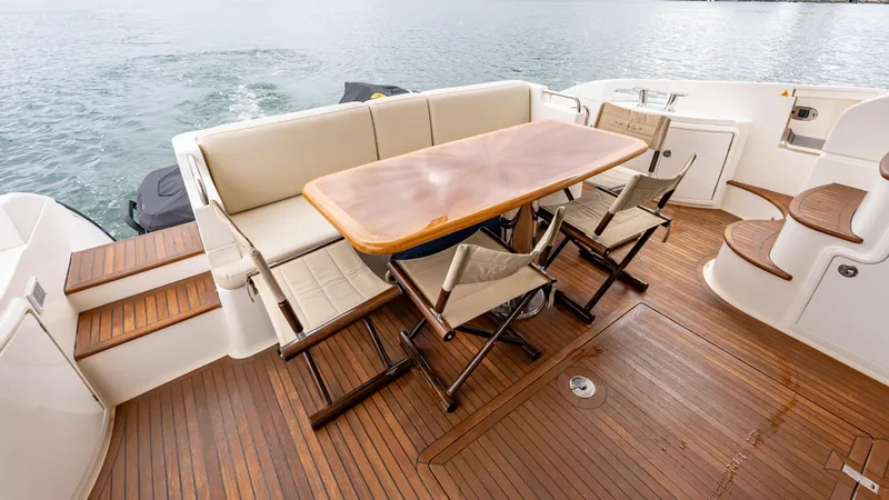 Christine Yacht Photos Pics 2011 Azimut 58 Flybridge yacht deck with wooden table and chairs, overlooking the water.