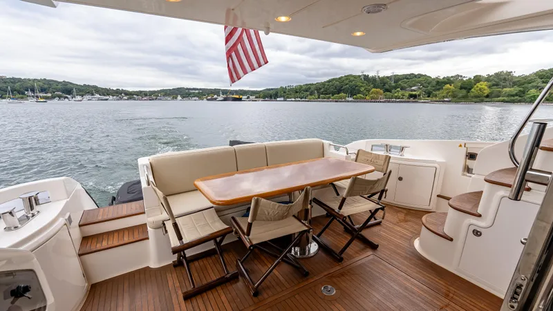 Christine Yacht Photos Pics 2011 Azimut 58 Flybridge yacht deck with dining area, overlooking serene waters and lush shoreline.