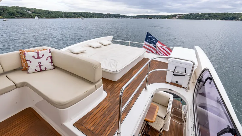 Christine Yacht Photos Pics Flybridge of 2011 Azimut 58 yacht with seating, sunbed, and American flag on calm water.