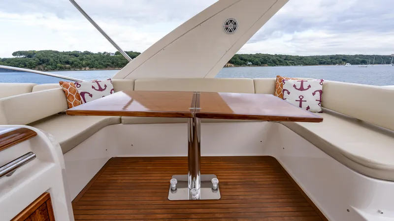 Christine Yacht Photos Pics Luxurious seating area on 2011 Azimut 58 Flybridge yacht with wooden table and anchor-themed cushions.