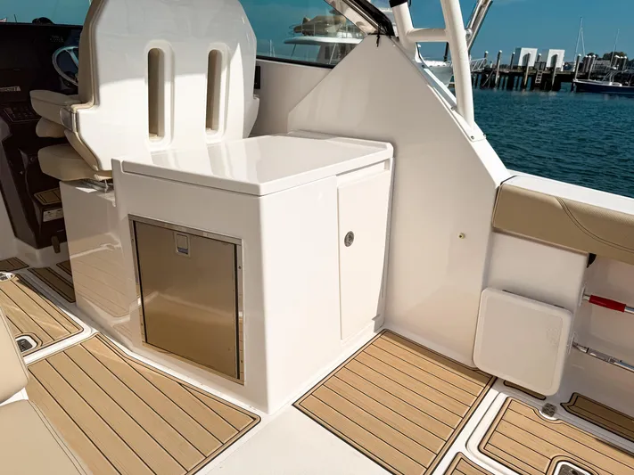 Adios Yacht Photos Pics 2018 Pursuit DC 325 Dual Console interior with seating and storage, docked by the water.