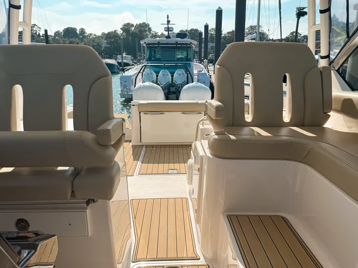Adios Yacht Photos Pics 2018 Pursuit DC 325 Dual Console boat interior with beige seating and wooden flooring.