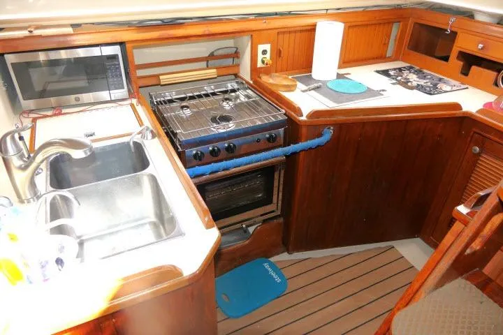Wild Blue Yacht Photos Pics Galley kitchen in 1999 Island Packet 45 sailboat with stove, sink, and microwave.