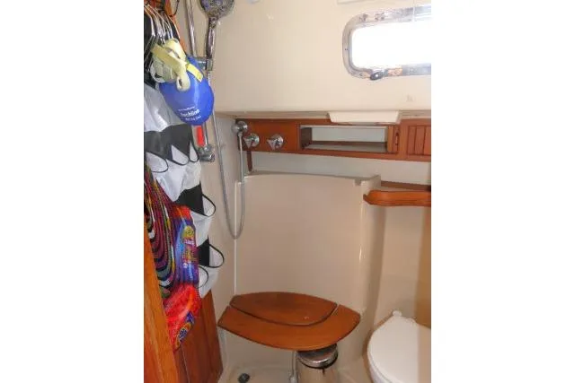 Wild Blue Yacht Photos Pics 1999 Island Packet 45 yacht bathroom with shower, wooden accents, and storage.