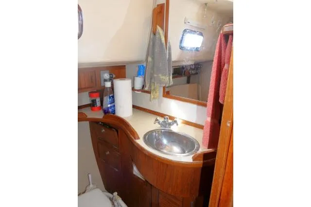 Wild Blue Yacht Photos Pics 1999 Island Packet 45 yacht bathroom with wooden cabinetry and stainless steel sink.