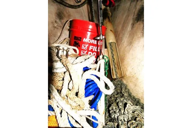 Wild Blue Yacht Photos Pics Storage compartment on a 1999 Island Packet 45 with ropes, chains, and a red bucket.