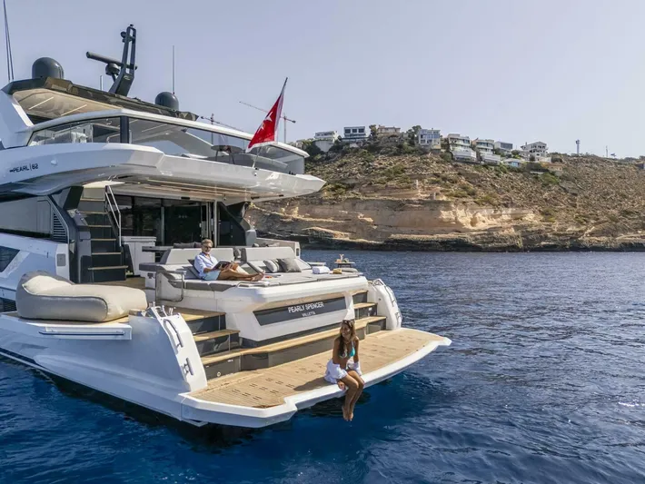82 Pearl Yacht Photos Pics Luxury Pearl 82 yacht cruising near rocky coastline, 2026 model, with people relaxing on deck.