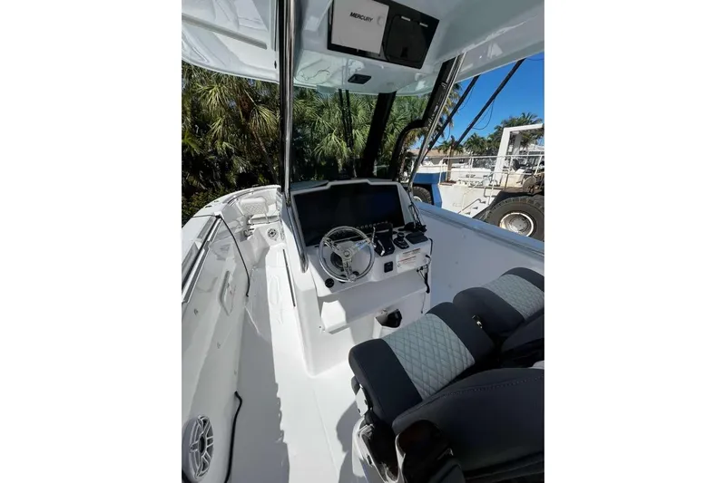  Yacht Photos Pics 2024 Bertram 28 CC boat cockpit with modern steering and controls, surrounded by lush greenery.