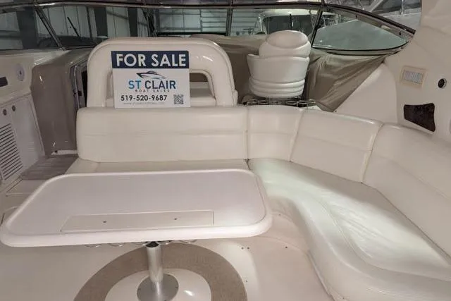 Tigress Yacht Photos Pics 2002 Sea Ray 550 Sundancer interior with "For Sale" sign, white seating, and table.
