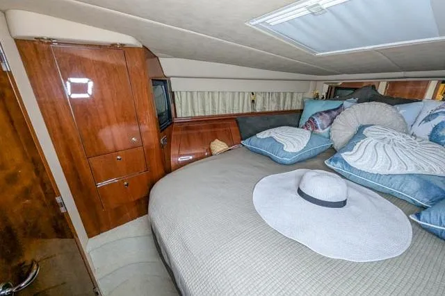 Tigress Yacht Photos Pics Luxurious cabin interior of 2002 Sea Ray 550 Sundancer with plush bedding and elegant wood finishes.