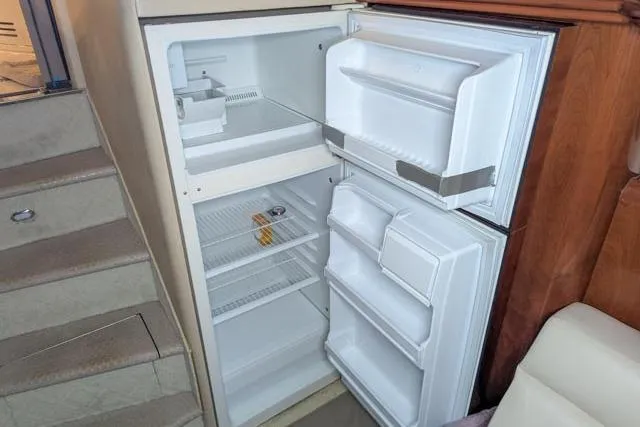 Tigress Yacht Photos Pics Open refrigerator inside 2002 Sea Ray 550 Sundancer yacht, showing empty shelves and door compartments.