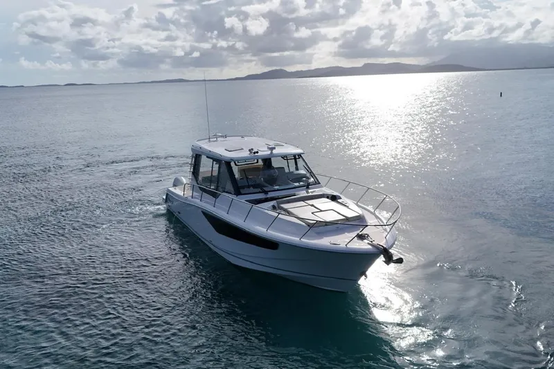  Yacht Photos Pics 2022 Boston Whaler 405 Conquest cruising on calm ocean waters under a cloudy sky.