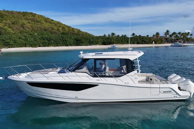  Yacht Photos Pics 2022 Boston Whaler 405 Conquest boat on clear blue water near a tropical beach.