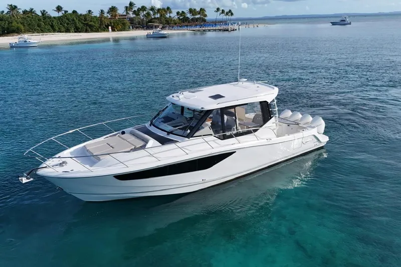  Yacht Photos Pics 2022 Boston Whaler 405 Conquest cruising in clear blue waters near a tropical island.
