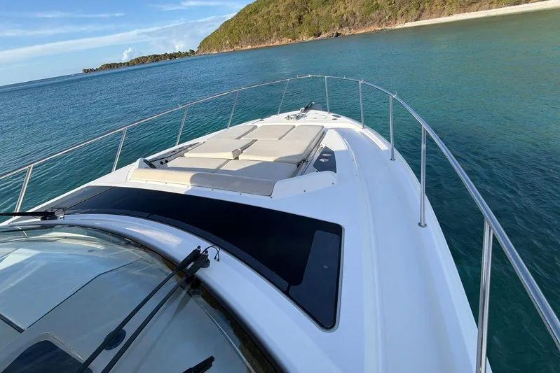  Yacht Photos Pics 2022 Boston Whaler 405 Conquest yacht on serene blue waters near a lush coastline.