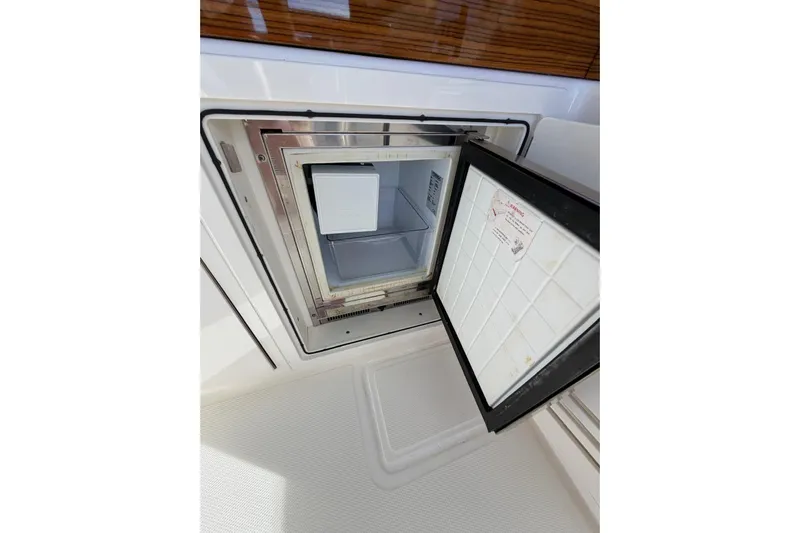 Yacht Photos Pics Open refrigerator on 2022 Boston Whaler 405 Conquest boat, showcasing interior storage space.