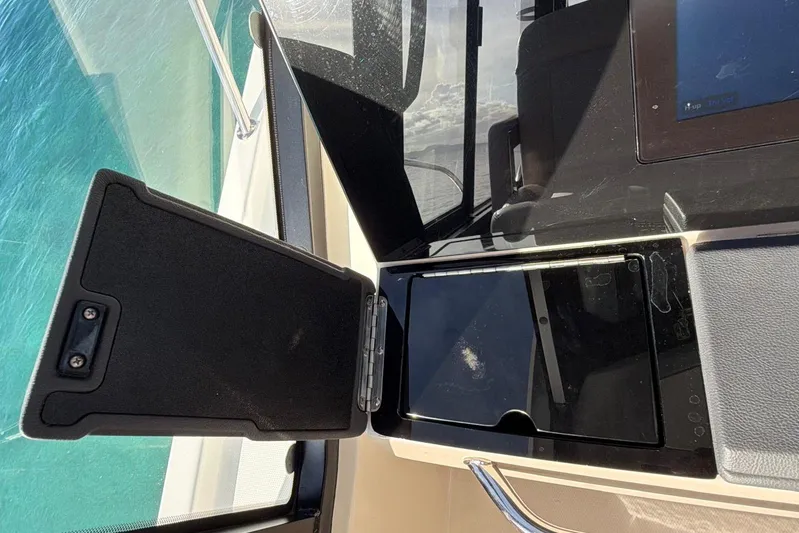  Yacht Photos Pics 2022 Boston Whaler 405 Conquest dashboard with open storage compartment, overlooking clear blue water.