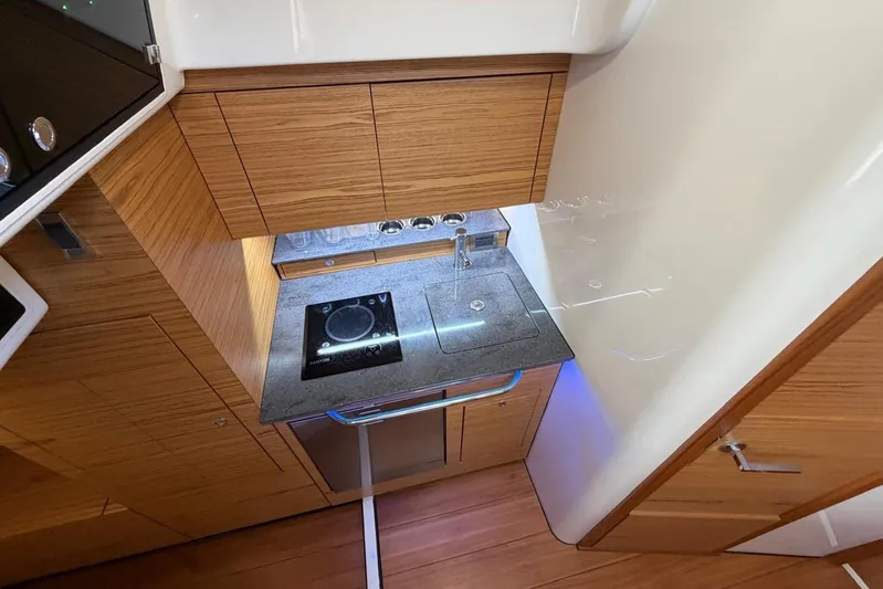  Yacht Photos Pics Modern kitchen area in 2022 Boston Whaler 405 Conquest boat, featuring sleek wood cabinetry.