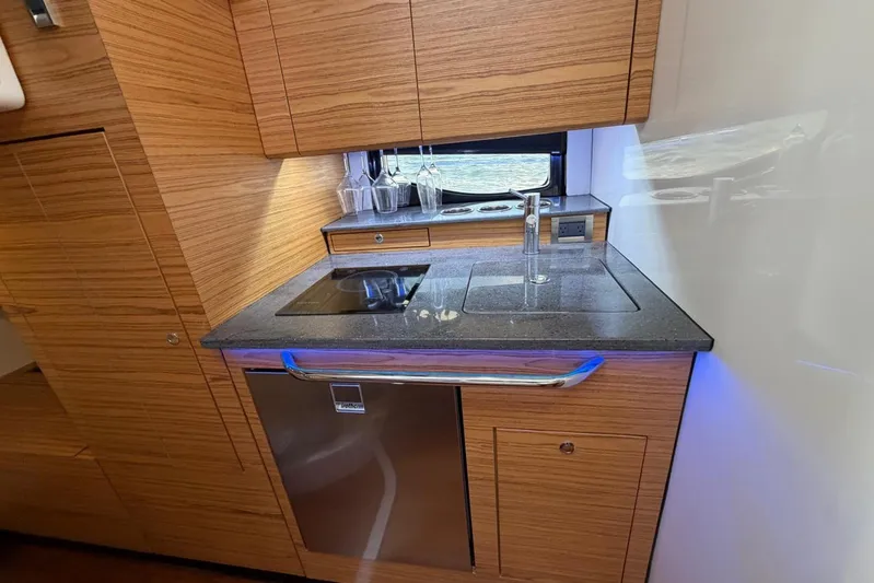  Yacht Photos Pics 2022 Boston Whaler 405 Conquest yacht kitchen with modern wood cabinetry and sleek appliances.