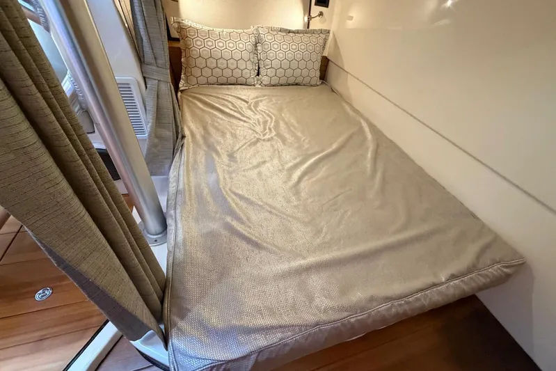  Yacht Photos Pics 2022 Boston Whaler 405 Conquest cabin bed with beige bedding and patterned pillows.