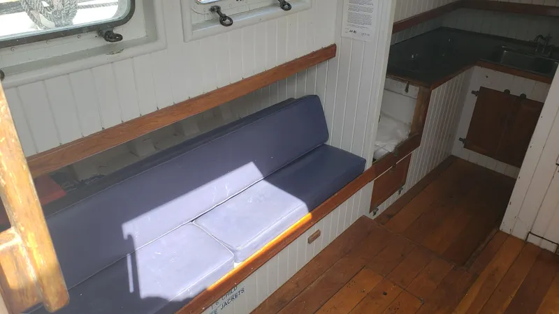 Daniel Webster Clements Yacht Photos Pics Interior of a 1996 Custom Biloxi Schooner with wooden floors and a blue cushioned bench.