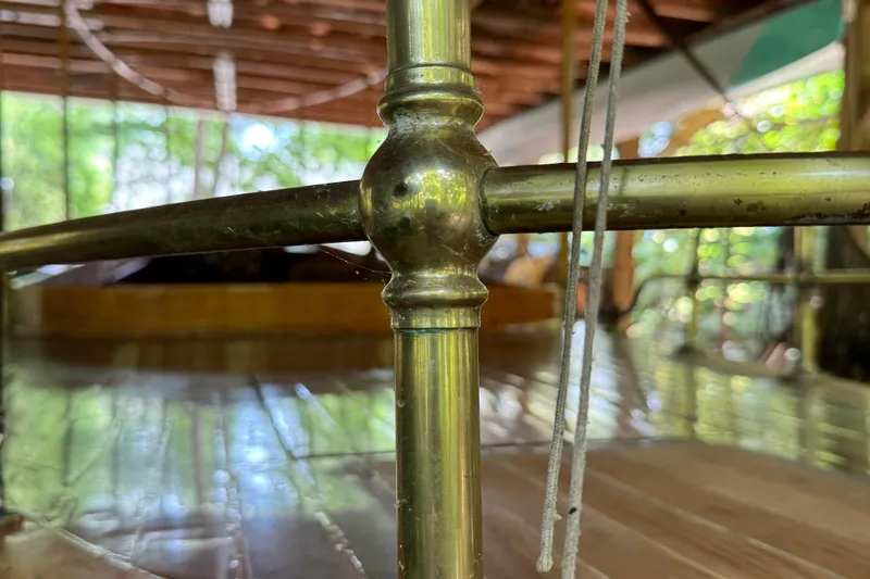 Annie Yacht Photos Pics Close-up of brass railing on 1989 Elco 30 Fantail Electric Launch, with wooden deck background.