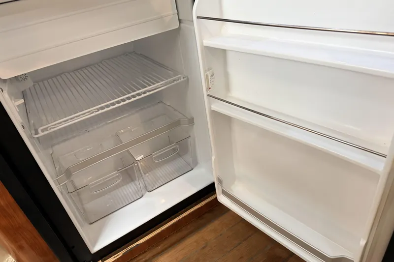  Yacht Photos Pics Open refrigerator inside a 2006 Sea Ray 340 Sundancer boat, showing empty shelves and drawers.