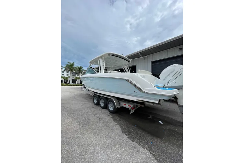  Yacht Photos Pics 2017 Boston Whaler 320 Vantage boat on trailer, parked near a building under cloudy sky.