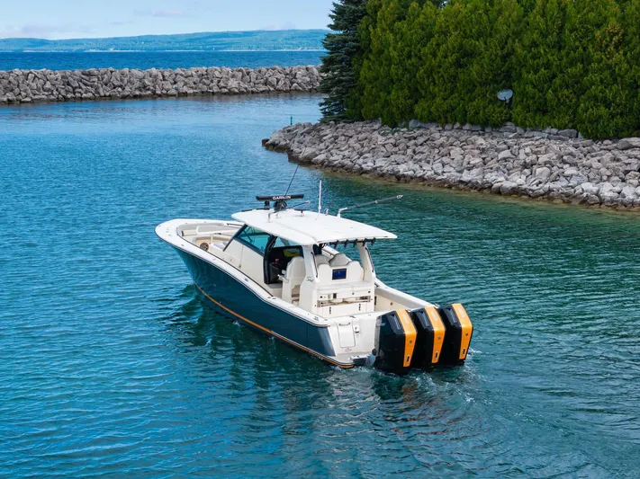 Yacht Photos Pics 2023 Scout 425 LXF boat cruising in a scenic waterway with rocky shoreline.
