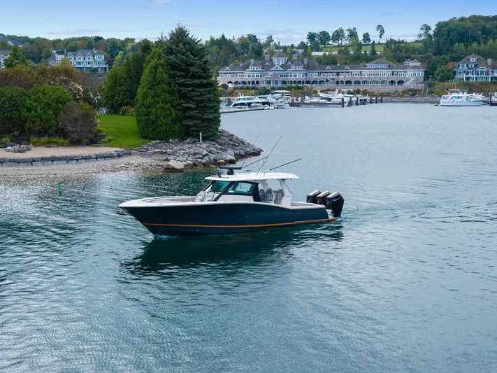  Yacht Photos Pics 2023 Scout 425 LXF boat cruising near a scenic waterfront with lush greenery.