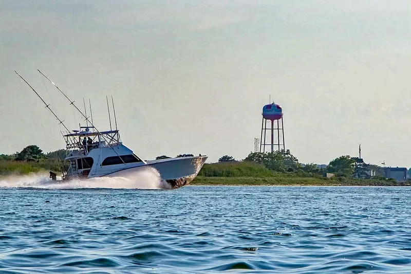 Euphoria Yacht Photos Pics Custom Carolina Precision Sportfish 2000 cruising near shoreline with water tower in background.