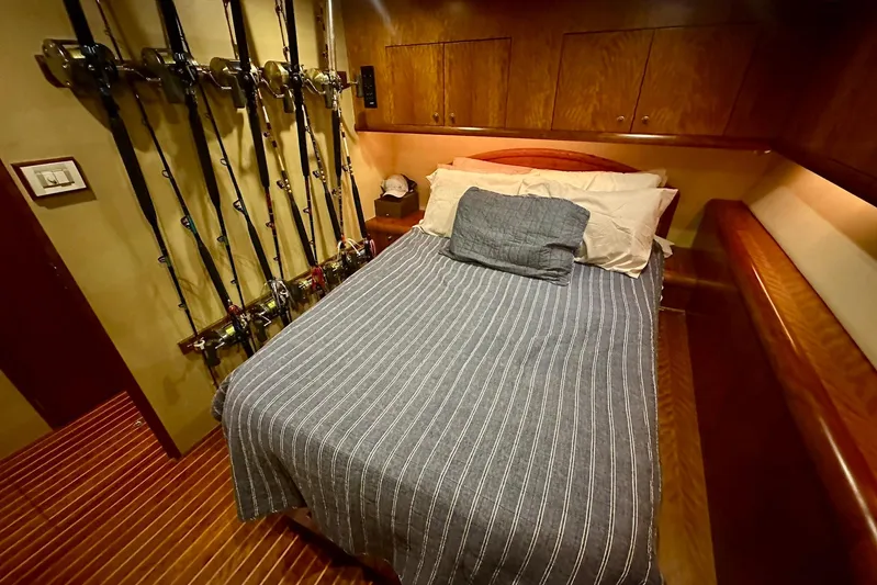Euphoria Yacht Photos Pics Cozy cabin interior of 2000 Custom Carolina Precision Sportfish with fishing rods and striped bedding.