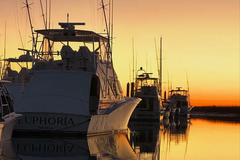 Euphoria Yacht Photos Pics Sunset view of Custom Carolina Precision Sportfish boats docked, reflecting on calm water.