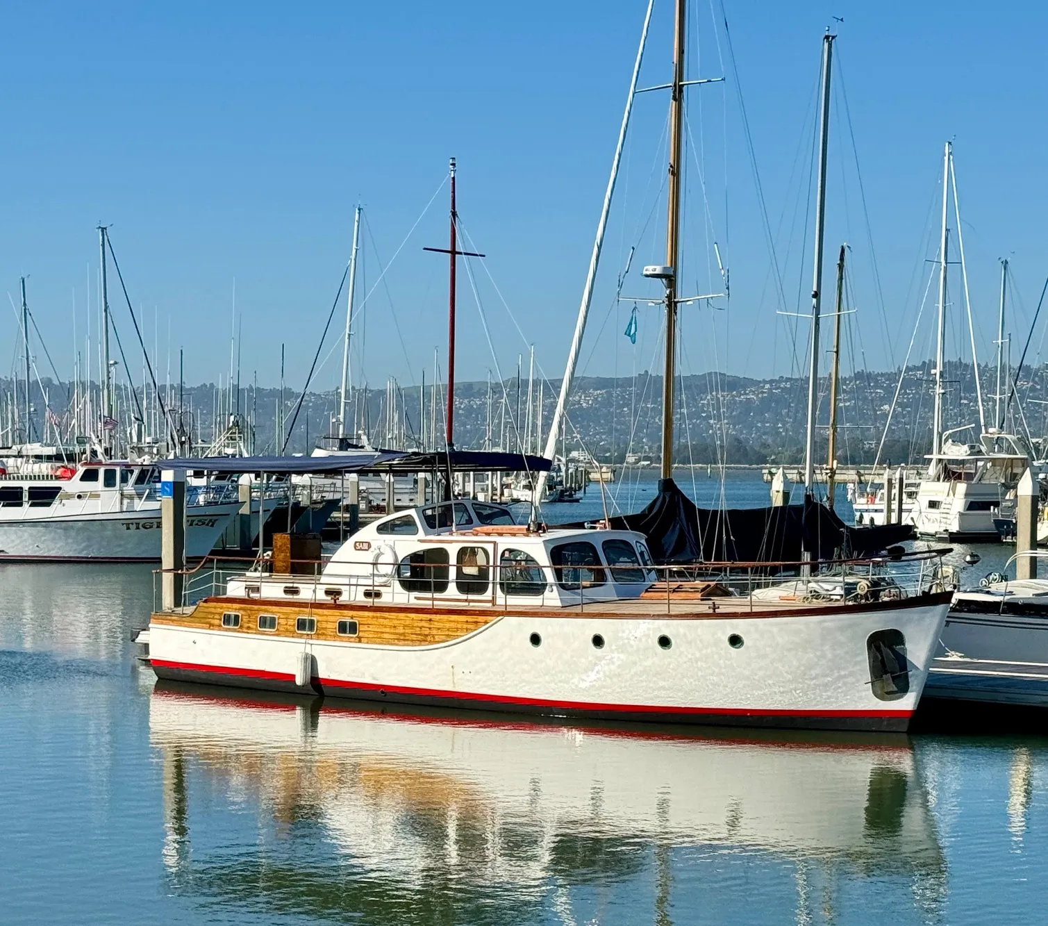 Classic 1966 Rampart 48 yacht docked in a marina, reflecting on calm water.