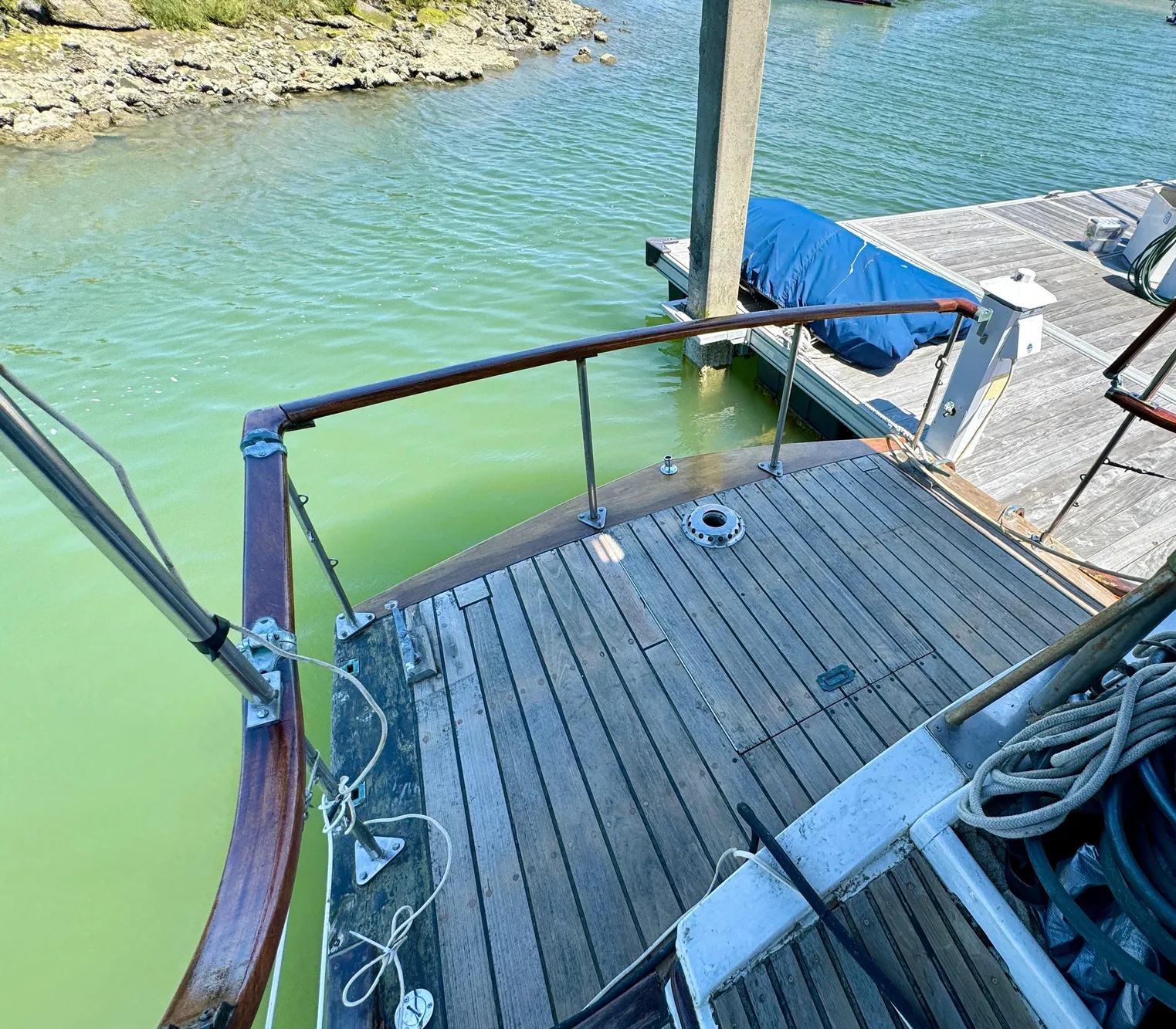 1966 Rampart 48 boat docked, featuring wooden deck and railing, moored by a pier.